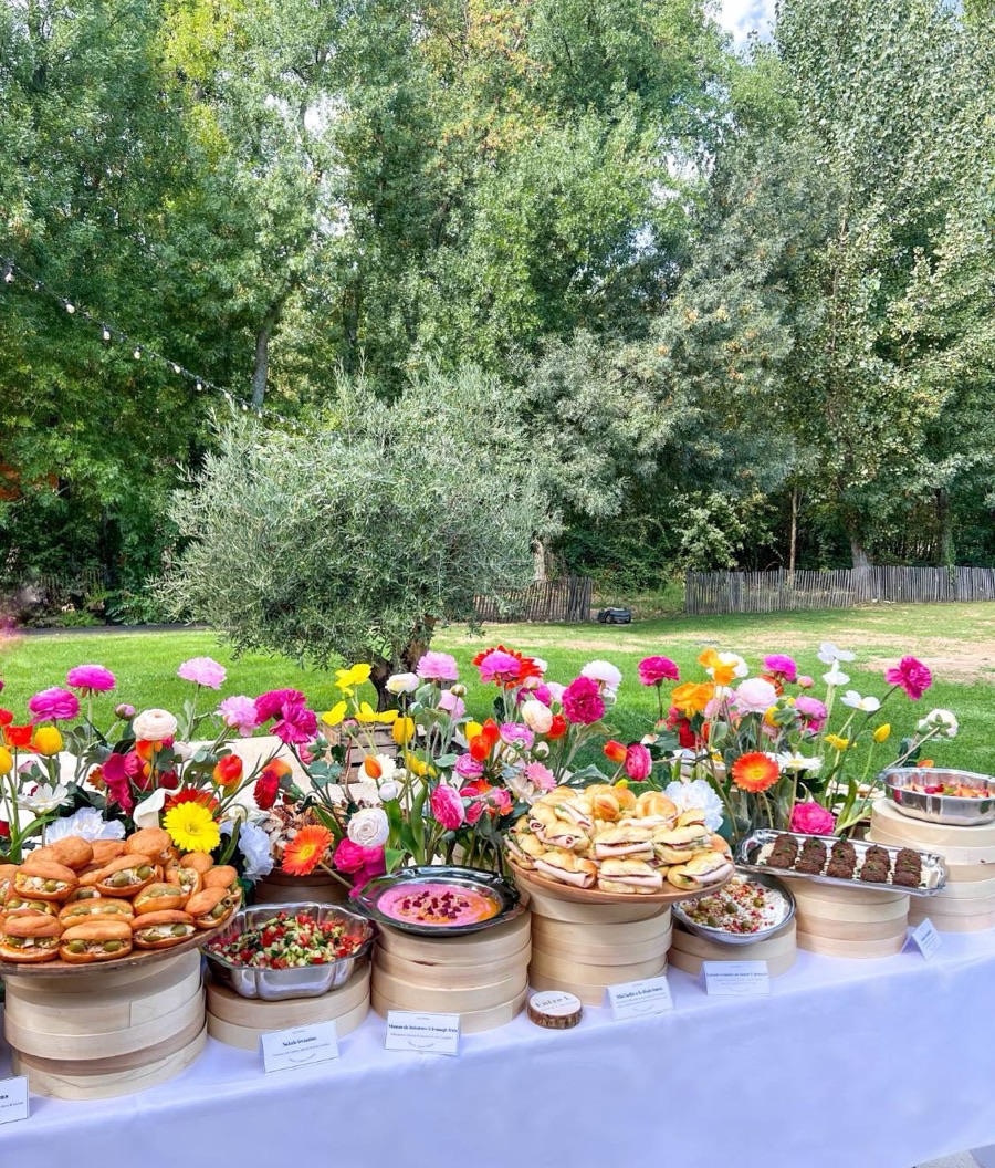 Buffet fleuri Entre L dressé dans un jardin arboré, devant un olivier