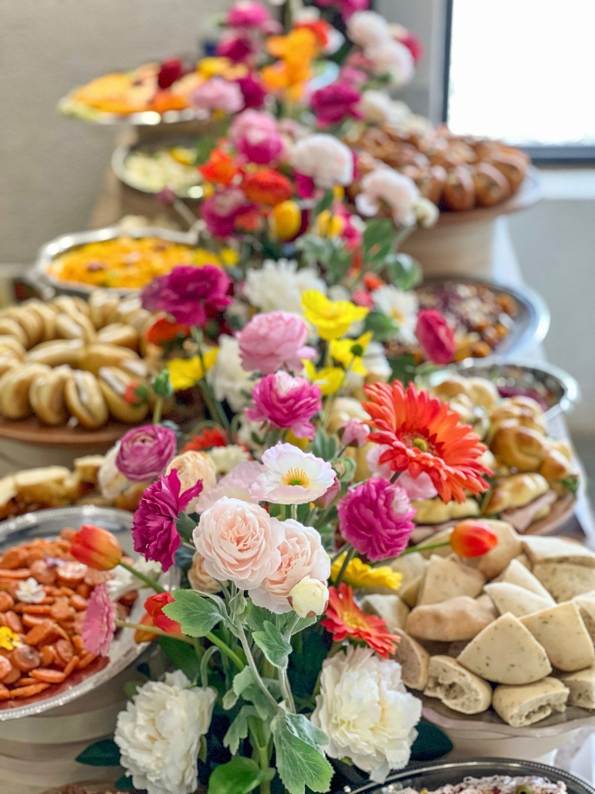 Fleurs colorées au milieu d'un buffet Entre L : pains pita maison, carottes marinées et petits pains garnis