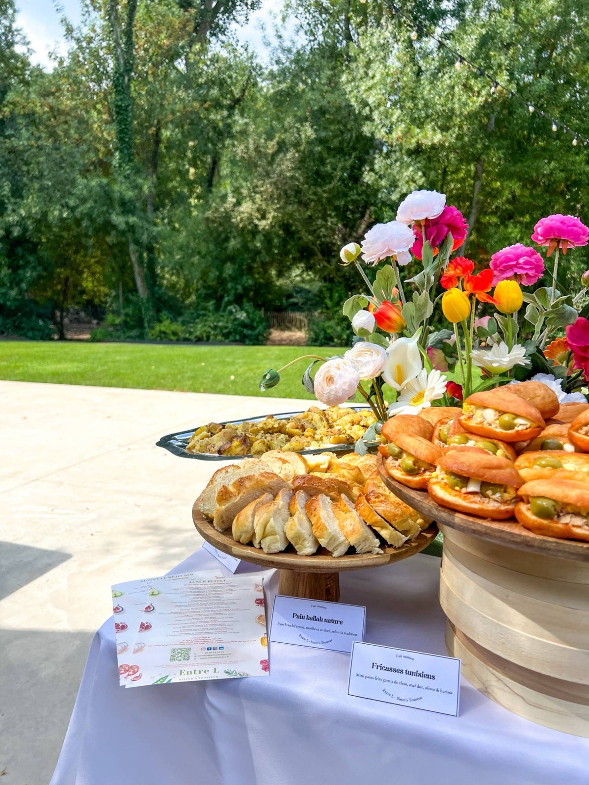Buffet Entre L dans un jardin : pain hallah nature et fricassés tunisiens faits maison, entourés de fleurs
