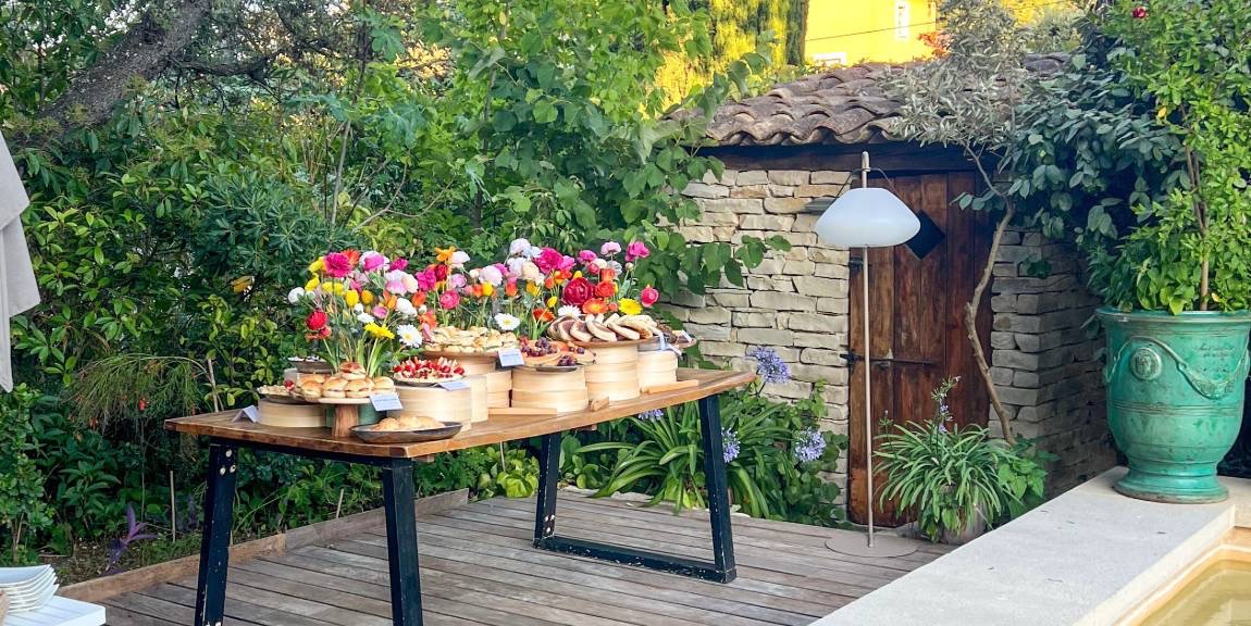 Buffet fleuri Entre L dressé au bord d'une piscine dans un jardin provençal près d'Aix-en-Provence, sous les arbres et un cyprès