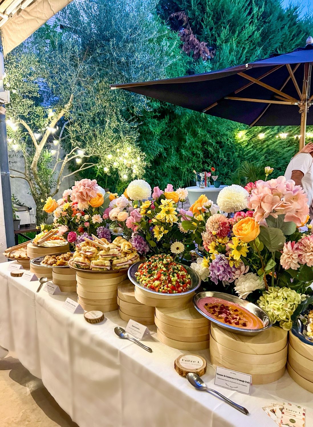 Buffet fleuri Entre L en soirée sous les guirlandes lumineuses : salade de légumes, mousse de betterave et petits pains