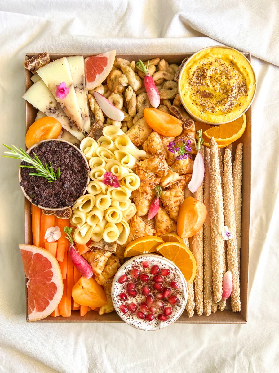 Grand plateau apéritif fait maison vu de dessus : tartinables, agrumes, gressins et fleurs