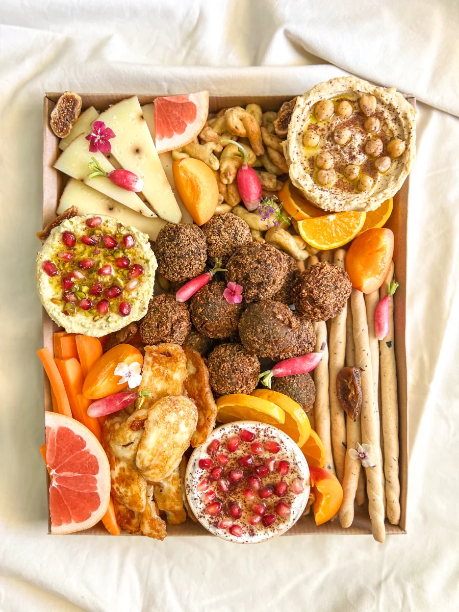 Plateau apéritif vu de dessus : falafels, tartinables, agrumes et légumes croquants